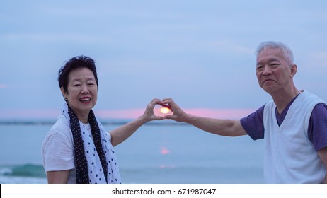 Asian Senior Couple Together At Sunrise Beach. New Year, New Chapter Concept