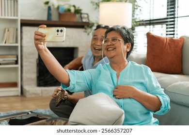 Asian Senior couple use smartphone for video call at home,selfie and mobile streaming and social media in retirement.Happy old asian man, woman and hug with phone for selfie,reading news app and relax - Powered by Shutterstock