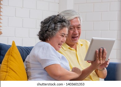 Asian Senior Couple Use Tablet Video Call And Talk To Grandchild.