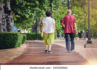 Asian Senior Couple Walking Together Along Walk Way In The Park 