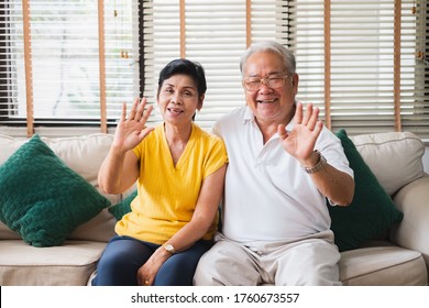 Asian Senior Couple Waving While Video Call With Family