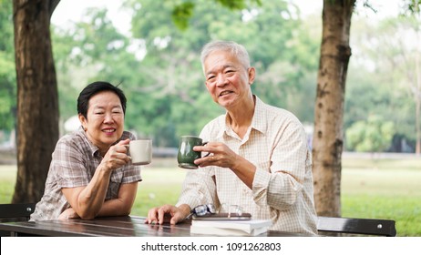 Asian senior elder couple relax drinking coffee in summer park, green background - Powered by Shutterstock