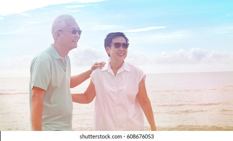 Asian Senior Elder Couple Walking Together On Beach By The Sea