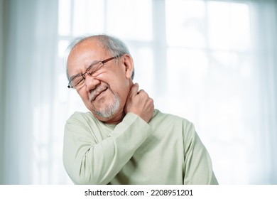 Asian Senior elderly man feek neckache his touching neck pain. Streesed old male suffer while sit on sofa at home. Health care and insurance retirement concept. - Powered by Shutterstock