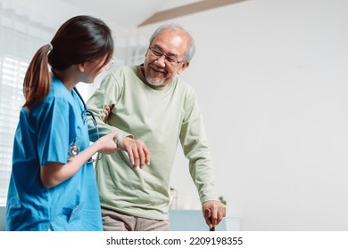 Asian senior elderly man patient doing physical therapy with caregiver. woman nurse helping get up from wheelchair for practice walking with walker at home, practice walk slowly at nursing home care.
