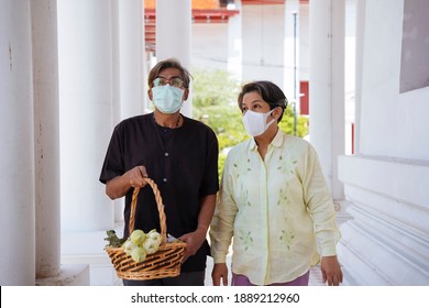 Asian Senior Elderly Old Couple Wear Mask In A Temple To Make A Merit.