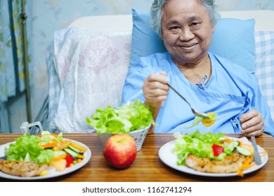 Asian Senior Or Elderly Old Lady Woman Patient Eating Breakfast Healthy Food With Hope And Happy While Sitting And Hungry On Bed In Hospital.
