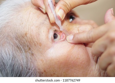 Asian Senior Or Elderly Old Lady Woman Dripping Medical Drops In Her Eye. Healthcare And Medical Concept.