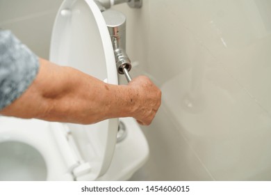 Asian Senior Or Elderly Old Lady Woman Patient Press Flush Toilet To Clean Before And After Use.              