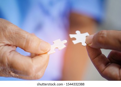 Asian senior or elderly old lady woman patient holding pieces of the puzzle with doctor in hospital ward : healthy strong medical concept                  - Shutterstock ID 1544332388