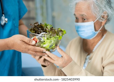 Asian Senior Or Elderly Old Lady Woman Patient With Mask Holding Vegetable Healthy Food With Hope And Happy While Sitting And Hungry On Bed In Hospital.