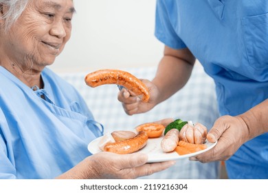 Asian Senior Or Elderly Old Lady Woman Patient Eating Breakfast Sausage And Vegetable Healthy Food With Hope And Happy While Sitting And Hungry On Bed In Hospital.