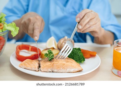 Asian Senior Or Elderly Old Lady Woman Patient Eating Salmon Steak Breakfast With Vegetable Healthy Food While Sitting And Hungry On Bed In Hospital.