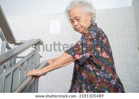 Asian senior or elderly old lady woman patient use handle at stairs security support in building, healthy strong medical concept.