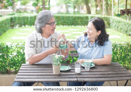 asian senior female pouring syrup to coffee cup, couple asian senior lover talk and drinking coffee in garden, retirement lifestyle
