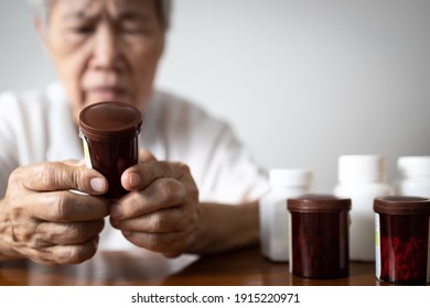 Asian Senior Grandmother Reading Medical Information Before Taking Of Medicine,read The Nutrition Label On A Bottle Of Vitamin Supplement,old Elderly People Checking Exp Date Or Side Effects In Drug