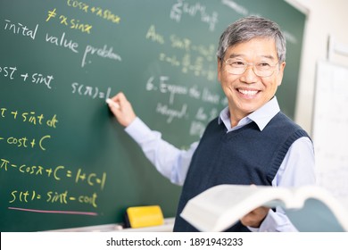 Asian Senior Male Calculus Professor Is Writing On Blackboard In The Classroom At College