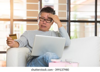 Asian Senior Male Having Trouble Shopping Online With Credit Card