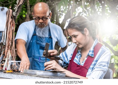 Asian Senior Male Leather Specialist Teaching Young Female Student How To Hammer Leather At Workshop,woman Learning In Art And Craft Class, Aged Craftsman Wears Apron Teach Handicraft To Asian Woman 