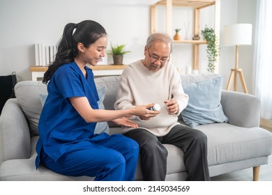 Asian Senior Male Patient Consult With Physician Nurse At Nursing Home. Caregiver Therapist Pharmacist Girl Hold Medicine Pills Bottle, Explain Prescription To Elderly Old Man In Living Room In House.