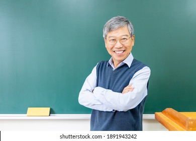 Asian Senior Male Professor Arm Crossed And Smile At You In Front Of Blackboard At College Classroom