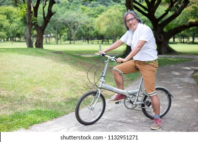asian senior man cycling in public park, retirement health promotion, he feeling happy and smile