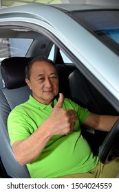 Asian Senior Man Driving A Car Showing Thumb Up Gesture.