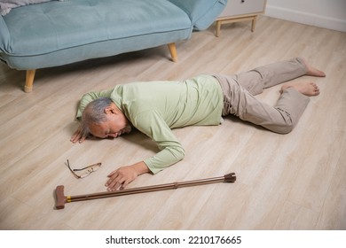 Asian Senior Man Falling Down Lying On Floor At Home Alone With Wooden Walking Stick In Living Room, Elderly Man Headache After Fall Down, Health Care And Medicine Concept