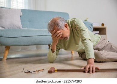 Asian Senior Man Falling Down Lying On Floor At Home Alone With Wooden Walking Stick In Living Room, Elderly Man Headache After Fall Down, Health Care And Medicine Concept