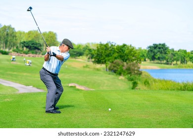 Asian senior man holding golf club hitting golf ball on fairway at country club in sunny day. Healthy retired elderly man golfer enjoy outdoor activity sport golfing at golf course on summer vacation - Powered by Shutterstock