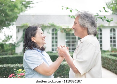 asian senior man holding hand of asian senior woman on garden background, retirement time, love together, hand in hand