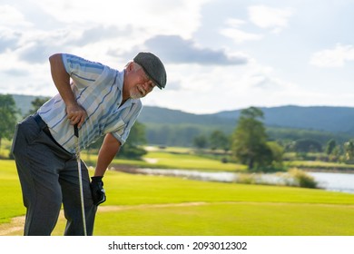 Asian Senior Man Holding His Injury Knee While Golfing At Country Club On Summer Vacation. Elderly Male Golfer Got Knee Pain While Outdoor Sport Workout. Senior People Medical And Healthy Care Concept