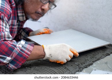 Asian Senior Man Laying Ceramic Tiles On The Floor, Home Repair By Yourself, Selective Focus