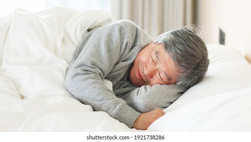 asian senior man lying on bed sleep well with smile in bedroom at home