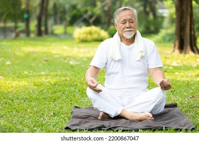 Asian Senior Man Meditating And Doing Yoga In The Park
