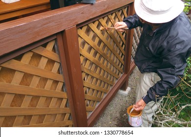 Asian Senior Man Painting Fence Outdoors