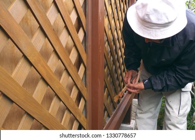 Asian Senior Man Painting Fence Outdoors