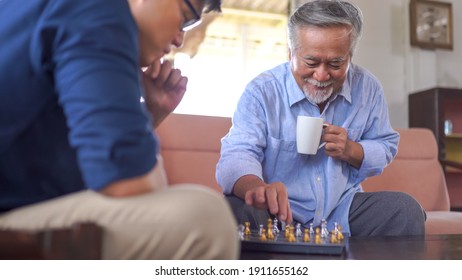 Asian Senior Man Playing Chess With Son At Home