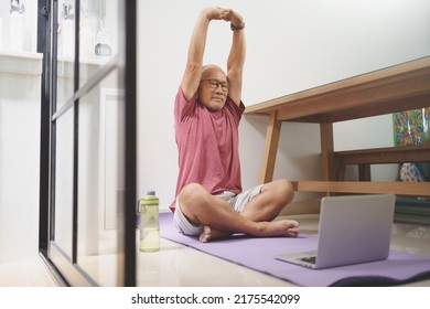 Asian Senior Man Stretching His Arms Before Yoga Exercise Online At Home.