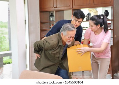 Asian Senior Man Is Suffering From Back Pain While Carrying Too Heavy Box While His Children Is Coming To Help And Taking Care Of Him