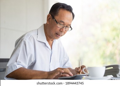 Asian Senior Man Using Calculator Thoughtful Look. Elderly Working Brain Exercise Concept.