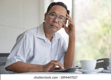 Asian Senior Man Using Calculator While Looking At Camera. Elderly Working Brain Exercise Concept.