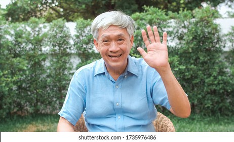 Asian Senior Man Video Call At Home. Asian Senior Older Chinese Male Using Mobile Phone Video Call Talking With Family Grandchild Kids While Lying In The Garden At Home In The Morning Concept.