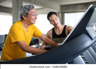 Asian Senior Man Walking Exercise On Treadmill With Personal Trainer Workout In Fitness Gym . Sport Trainnig , Retired , Older , Mature, Elderly , Smiling .rehab