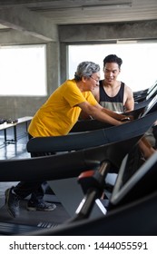 Asian Senior Man Walking Exercise On Treadmill With Personal Trainer Workout In Fitness Gym . Sport Trainnig , Retired , Older , Mature, Elderly , Smiling .rehab