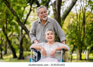 Asian senior man with wife in wheelchair walking relaxing happy outdoors in the park, Leisure activities of retirees, elderly health care concept. - Powered by Shutterstock