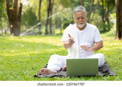 Asian Senior Man Workout And Doing Yoga With Online Training From Laptop Computer In The Park