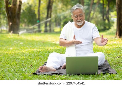 Asian Senior Man Workout And Doing Yoga With Online Training From Laptop Computer In The Park