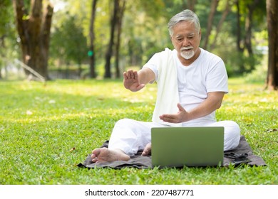 Asian Senior Man Workout And Doing Yoga With Online Training From Laptop Computer In The Park