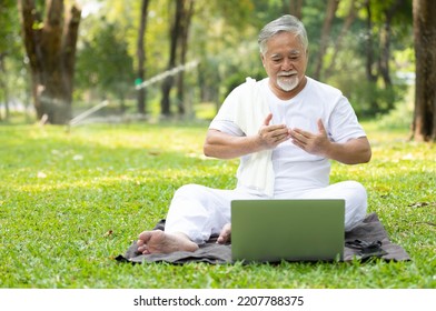 Asian Senior Man Workout And Doing Yoga With Online Training From Laptop Computer In The Park